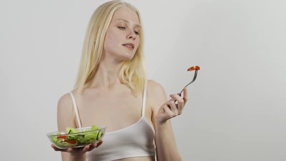 Young Cheerful Woman Eating Tomato and Cucumber Salad and Dancing Vigorously