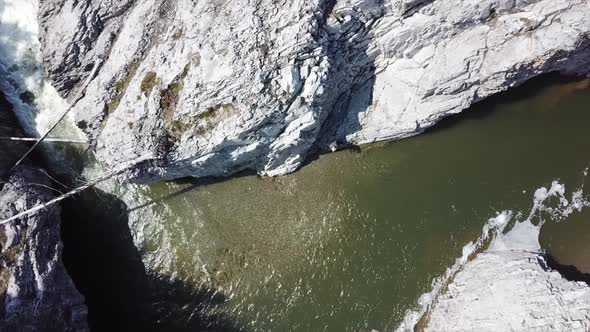 Aerial Footage Zoom Out On Man Cliffs & Creek Rapids