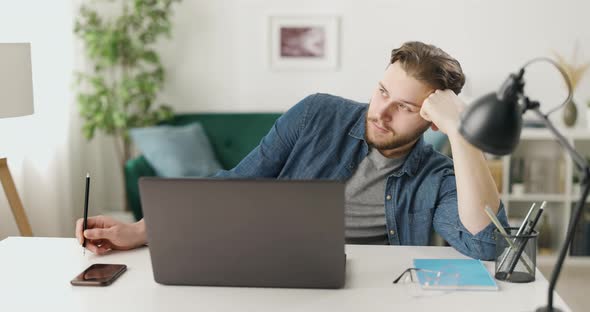 Thoughtful Man with Laptop at Home