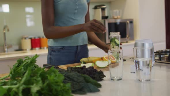 Midsectin of african american attractive woman preparing smoothie in kitchen alt