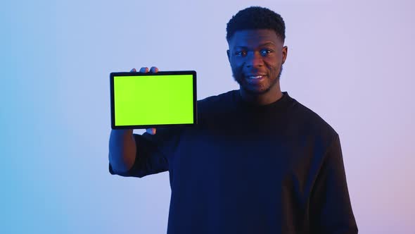 Man Showing a Tablet with a Green Screen at the Camera  Hand Gestures alt
