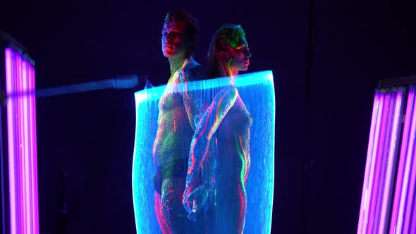 Couple with Neon Body Art Standing Near Uv Lamp Backstage