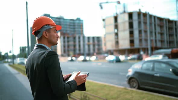 Architect Looking Digital Pad and Comparing Project with Building alt