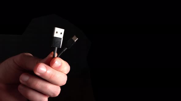 Two Usb Connectors In Hand On A Black Background
