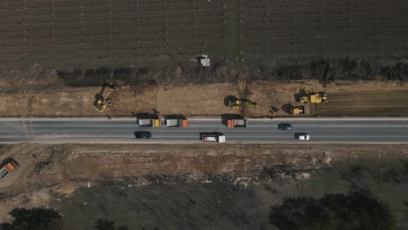 Excavator Digging Ground and Load It Into Dump Truck on Road alt