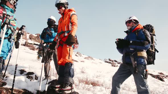 Group of Climbers Standing and Drinking Tea From a Thermos Bottle alt