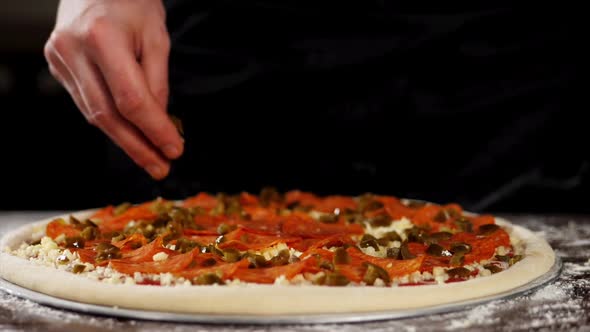 The Hand is Sprinkling the Pickled Paprika on the Pizza Closeup in Slow Motion
