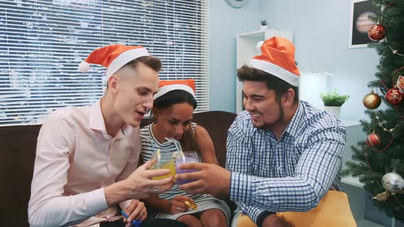 Close Up of Two Boys and a Girl in Santa Hats Making Cheers and Blowing Party Whistles alt