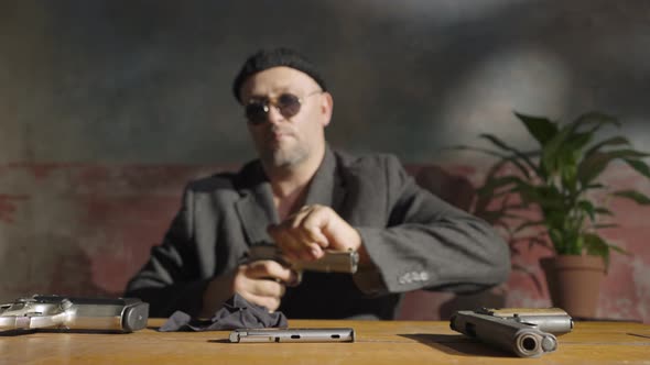 Focus on Hands of the Man Wiping the Gun alt