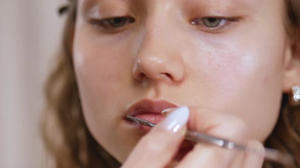 Preparing the Model's Skin for Applying Makeup. Lip Treatment with a Spatula and Lip Balm. Close Up. alt