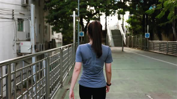 Asian woman athlete walking on the street after a run.