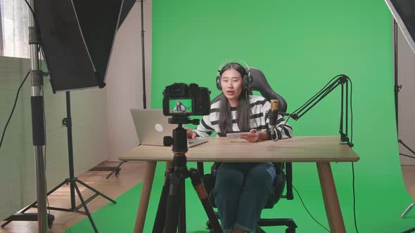 Camera Recording Asian Woman Reading Comment On Computer While Playing Game On Mobile Phone On Green alt
