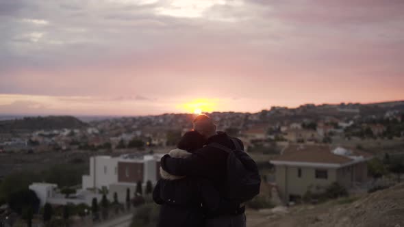Couple Embracing and Looking at Panoramic City View at Sunset