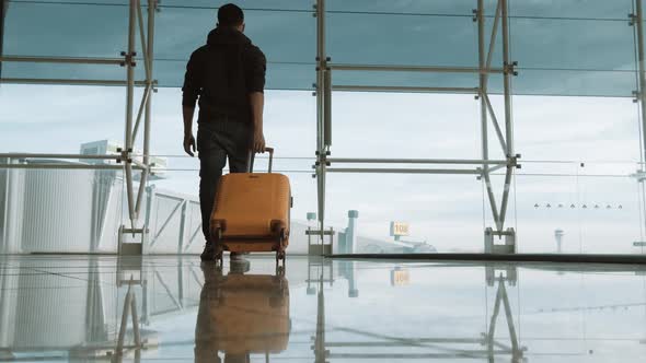 Passenger with baggage at international airport walking to terminal gate