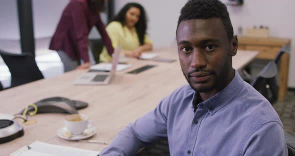 Portrait of smiling african american businessman looking at camera in modern office alt