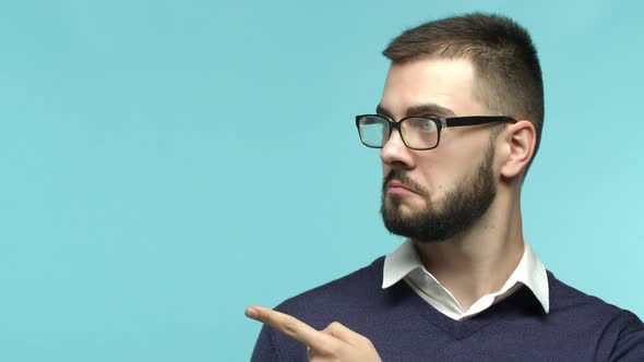 Close Up of Handsome Man with Beard and Glasses Turn Head Pointing Finger Left at Copy Space for