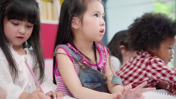 Multi-ethnic young boys and girls happy funny study and play painting on paper at elementary school. alt