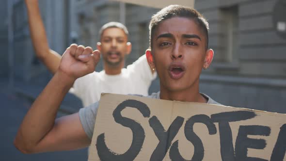 Two mixed race men on a protest march holding placards raising hands and shouting alt