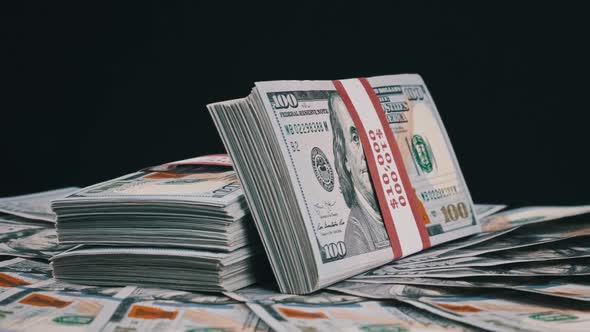 Bundles of Dollars Lying on a Pile of Money and Rotate on Black Background alt