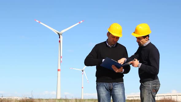 Two Engineers at Work with Wind Turbine on Background alt