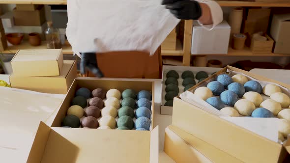 Woman packing handmade soap in cardboard boxes