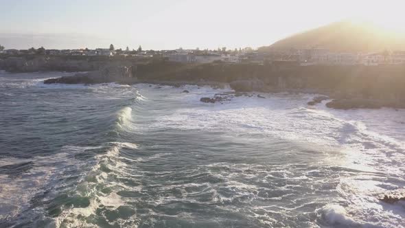 Aerial over a rocky coastline and small town with waves breaking