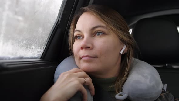 Young Beautiful Woman Listening Music in Headphones Sitting in Backseat in Car