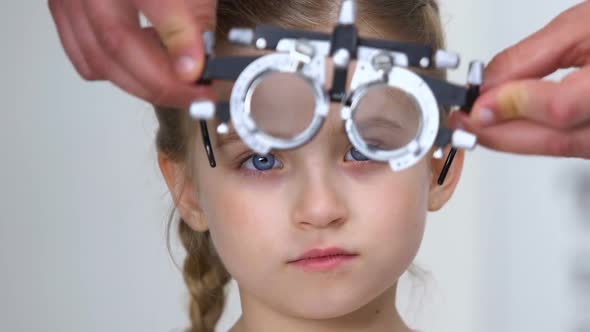 Pretty Female Kid in Optical Trial Frame, Optometrist Choosing Proper Lens alt