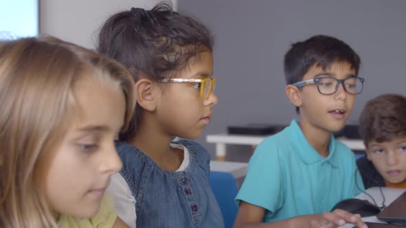 Smart Schoolboy in Glasses Helping Classmates To Do Task alt