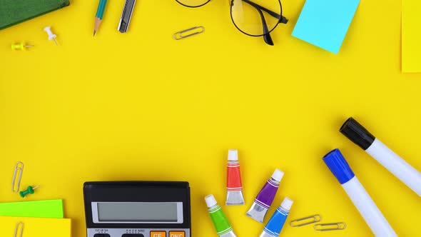 Colorful office and education supplies on yellow background with copy space in the middle