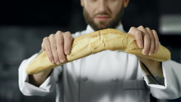 Chef Breaking French Bread in Slow Motion. Closeup Baker Hands Breaking Bread. alt