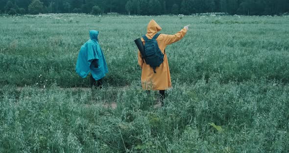 Man and Woman in Raincoats are Engaged in Hiking and Discussing Further Route alt
