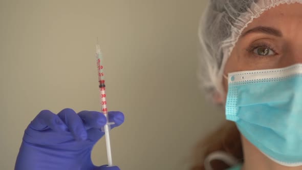 Closeup Portrait of Doctor or Nurse Wearing Medical Mask and Disposable Hat Filling a Syringe with alt