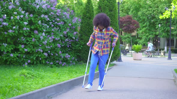 African American Woman with an Afro Hairstyle with a Broken Leg on Crutches alt