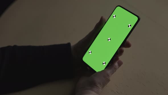 Handheld Shot of Old Female Hands Holding Smartphone with Green Screen Over Wood Vintage Table with