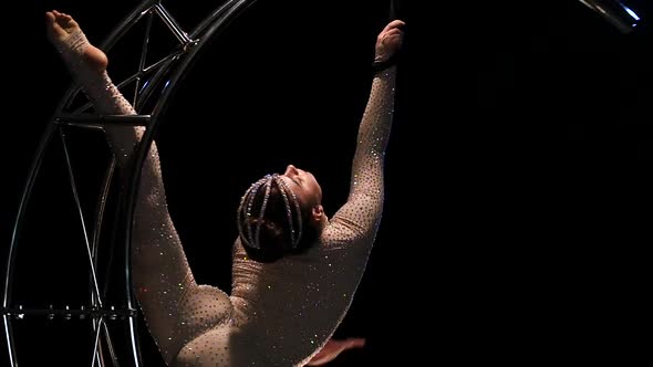 Acrobatic Movement on a Rotating in the Form of a Month Performs Tricks in a Dark Studio. Black alt