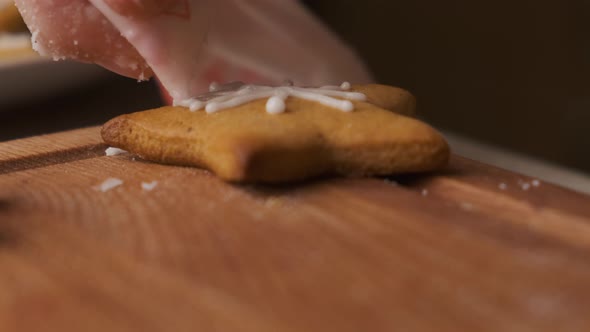 Close Up Woman Hand Decorating Christmas Gingerbread in the Shape of Star with Icing on the Wooden alt