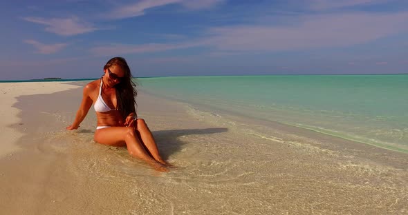 Pretty beauty model on holiday in the sun on beach on sunny blue and white sand 4K background alt