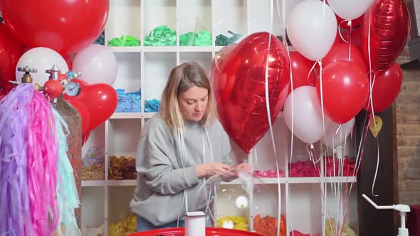 Woman Ties with a Ribbon a Round Transparent Balloon with White Feathers Inside alt