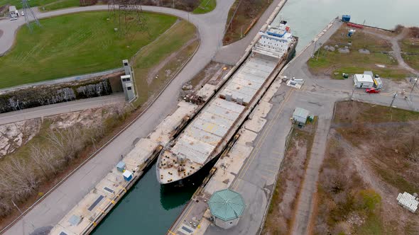 High quality, 4K aerial view of a bulk carrier ship maneuvering inside a canal.