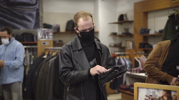 Young Man in Covid-19 Face Mask Sneezing in Men's Clothing Shop, Customers Running Away From alt