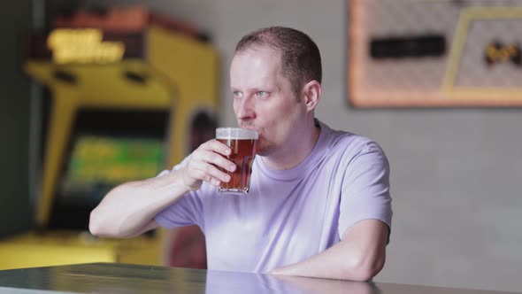 Young Man Drinking Beer a Bar alt