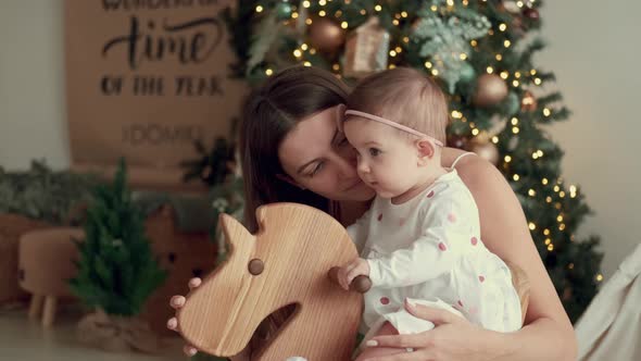 Mom Shakes the Baby on a Swing Near the Christmas Tree alt