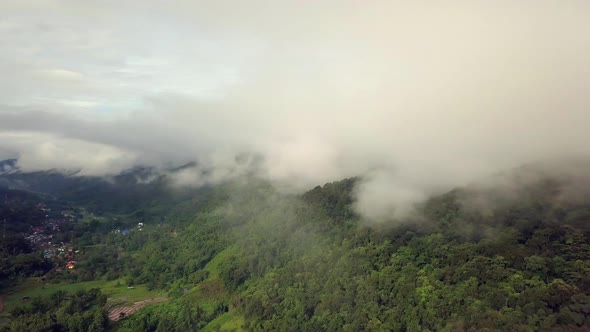 Aerial view flying thru the morning rain cloud covered tropical rain forest mountain landscape durin alt