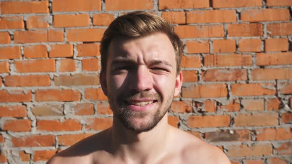 Close Up of Strong Bearded Man Looking Into Camera with Happy Face Smiling Illuminated By the Sun alt