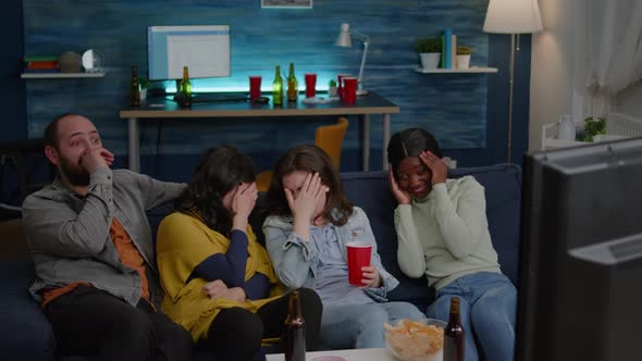 Group of Multiracial People Sitting Comfortable on Couch While Watching Thriller Movie alt