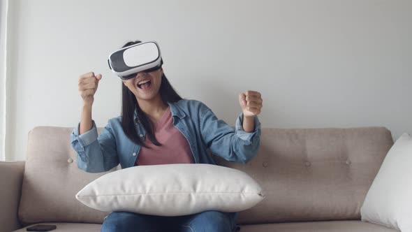 Attractive portrait young Asian woman wearing VR headset in the living room.