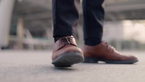 Close up of brown shoes Asian businessman wearing a suit standing at the urban street.