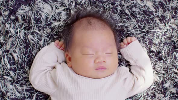 Top view happy newborn baby lying on a carpet looking at camera alt