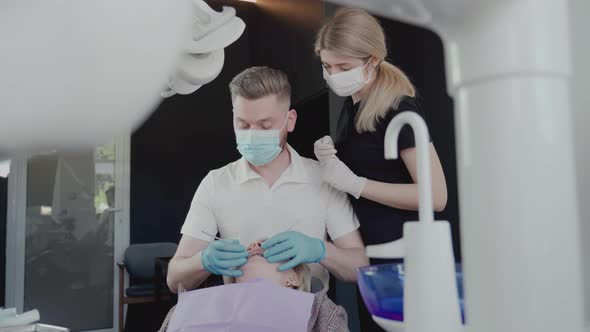 Two dentists, a man and a woman in protective masks and medical gloves